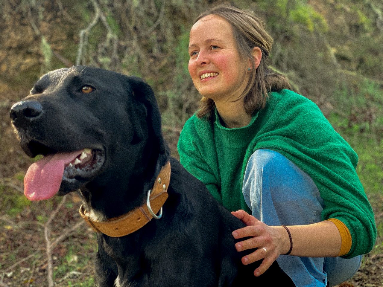 Mira Stark mit ihrem schwarzen Hund im Wald