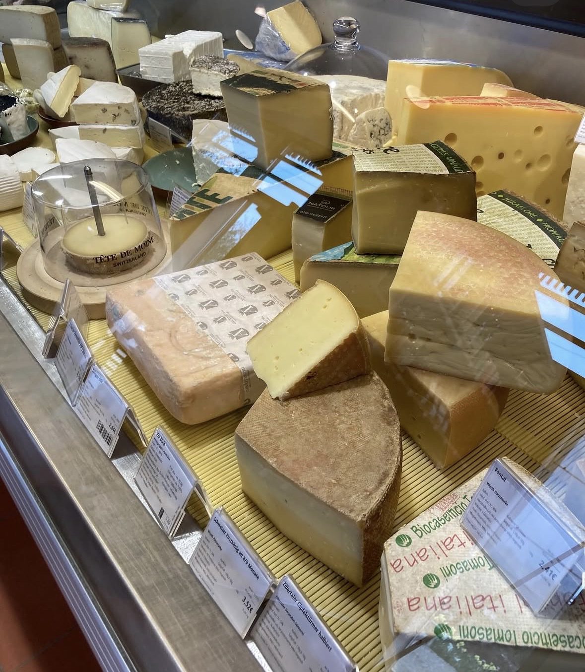 Käsetheke mit Bergkäse, Tête de Moine und italienischem Käse