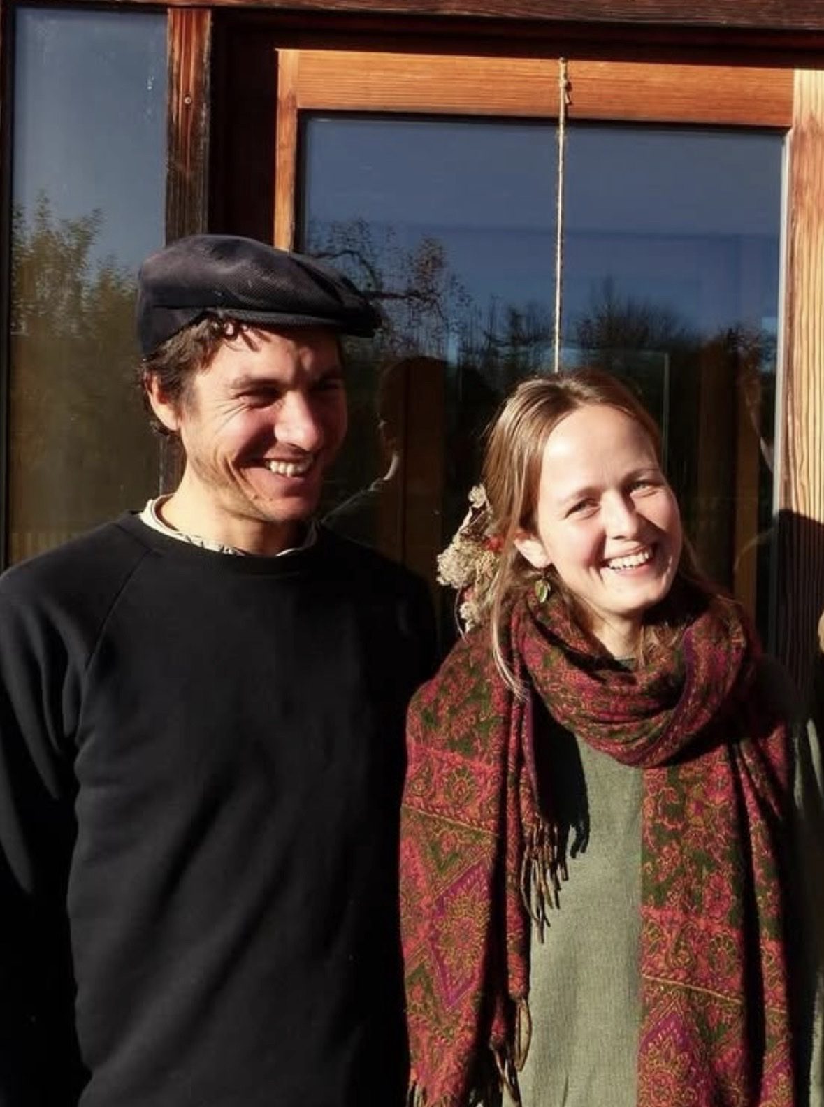 Konstantin und Mira Stark lachend in der Herbstsonne vor einem Holzfenster